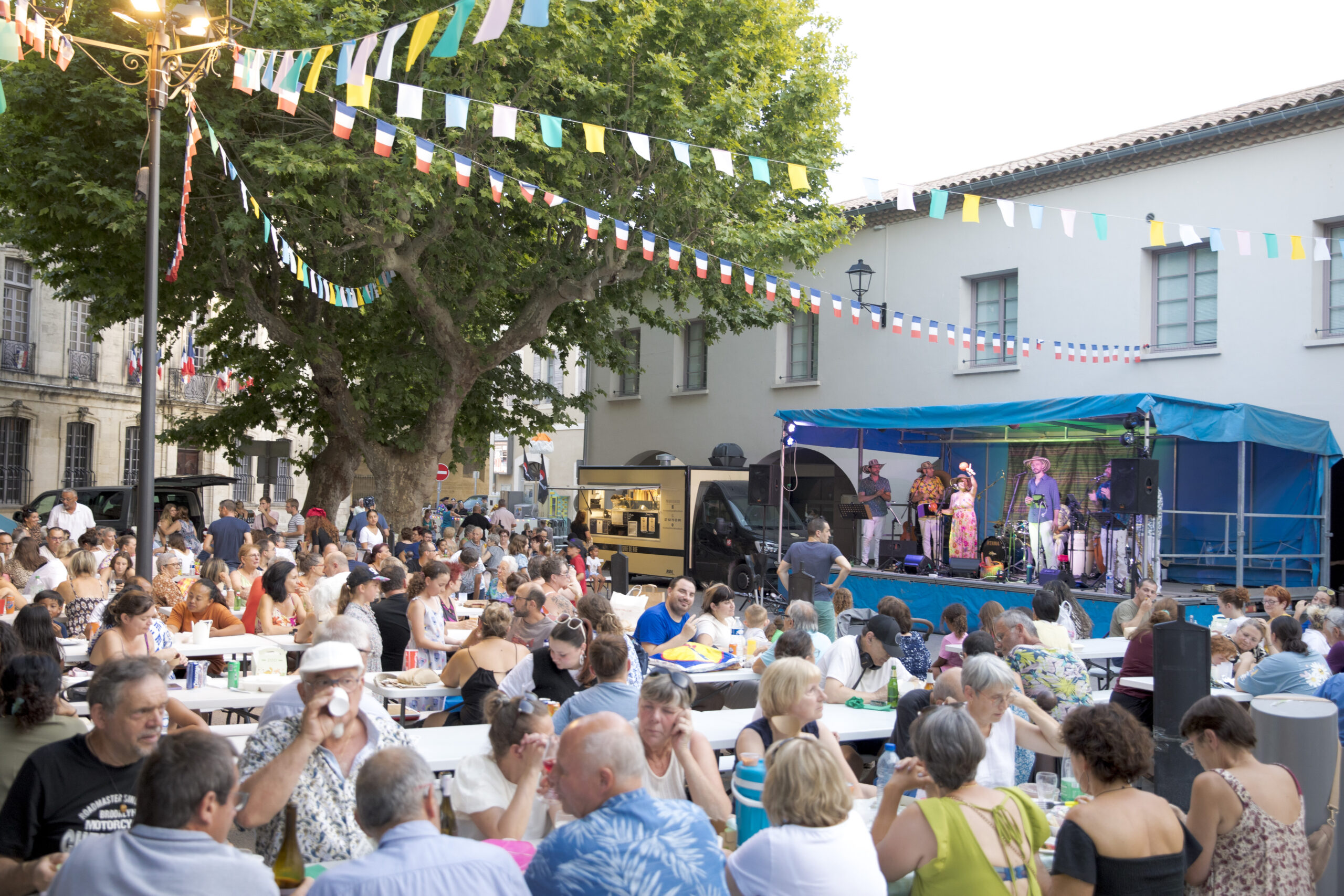 Repas partagé place de la Mairie, sous les platanes