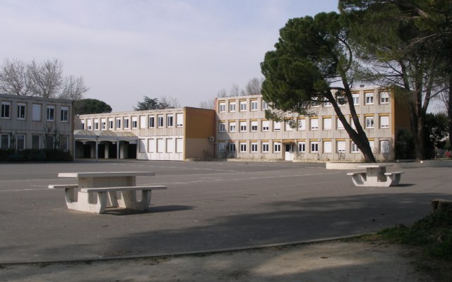 La cour du collège Paul-Valéry, avec ses tables de pique-nique en béton, devant les bâtiments de classes et de grands pins
