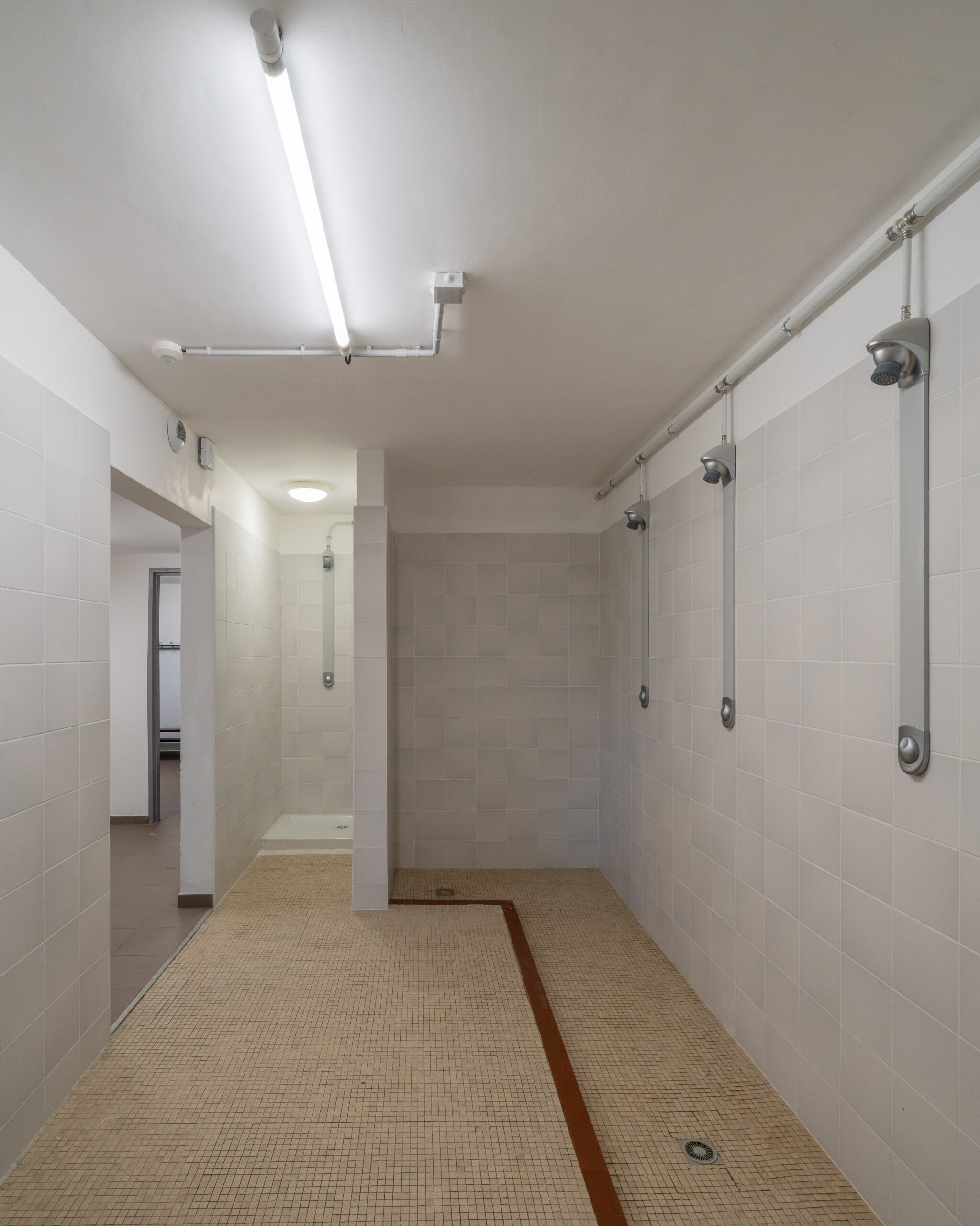 Douches des vestiaires rénovés du gymnase, carrelage clair