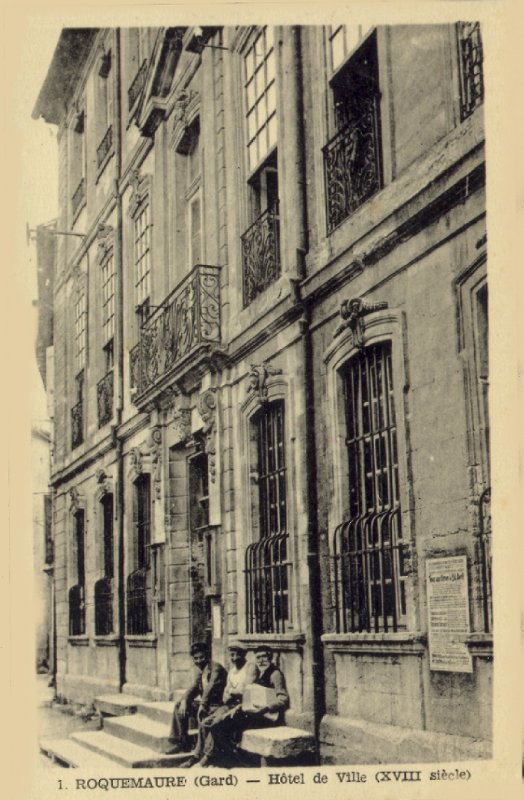 Carte postale ancienne « Roquemaure (Gard), Hôtel de ville (XVIIIe siècle) » : façade à balcons en fer forgé, trois hommes assis sur les marches de l’entrée