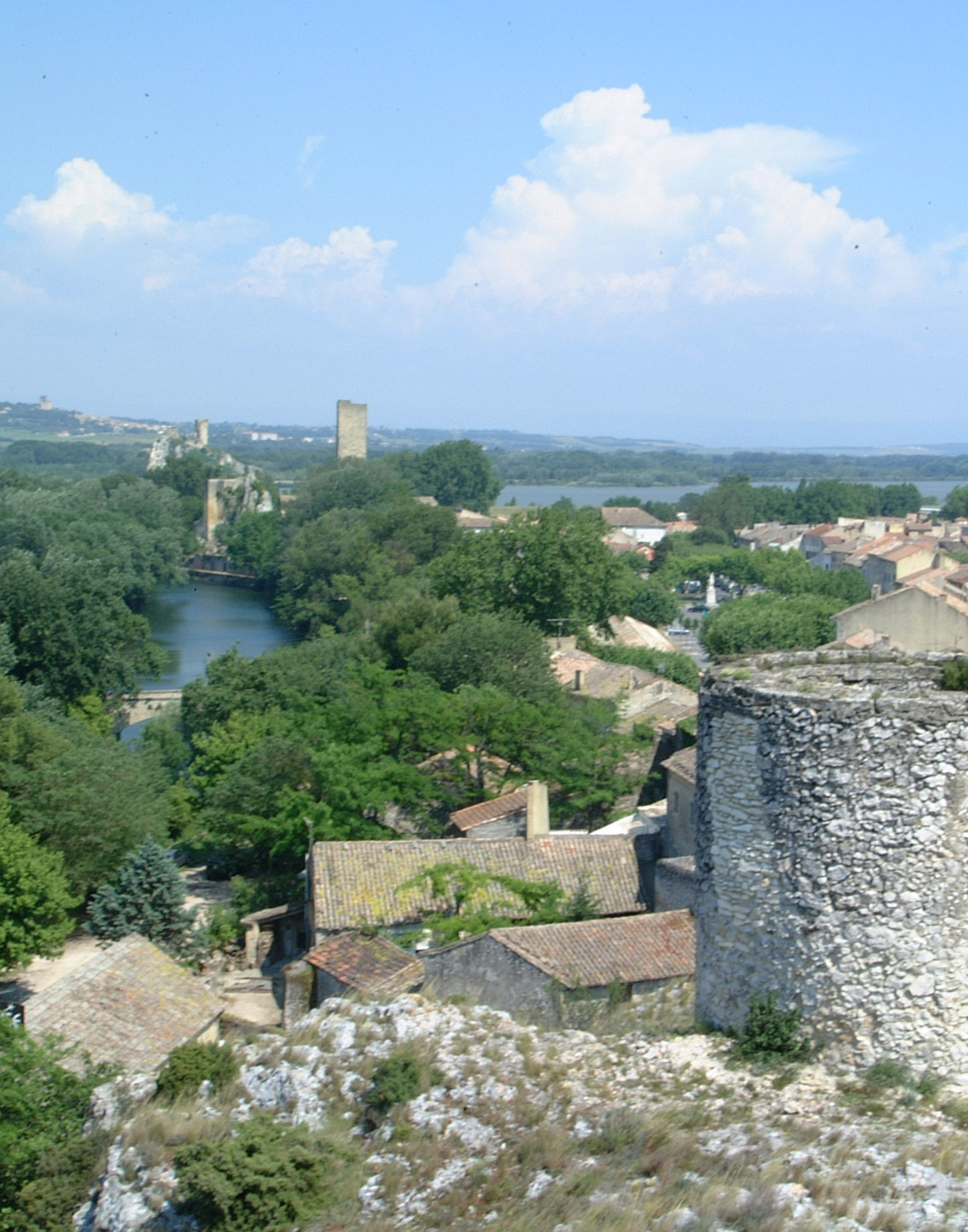 Roquemaure vue de la colline Saint-Jean : une tour ronde en pierre au premier plan, les toits du village et le Rhône au loin