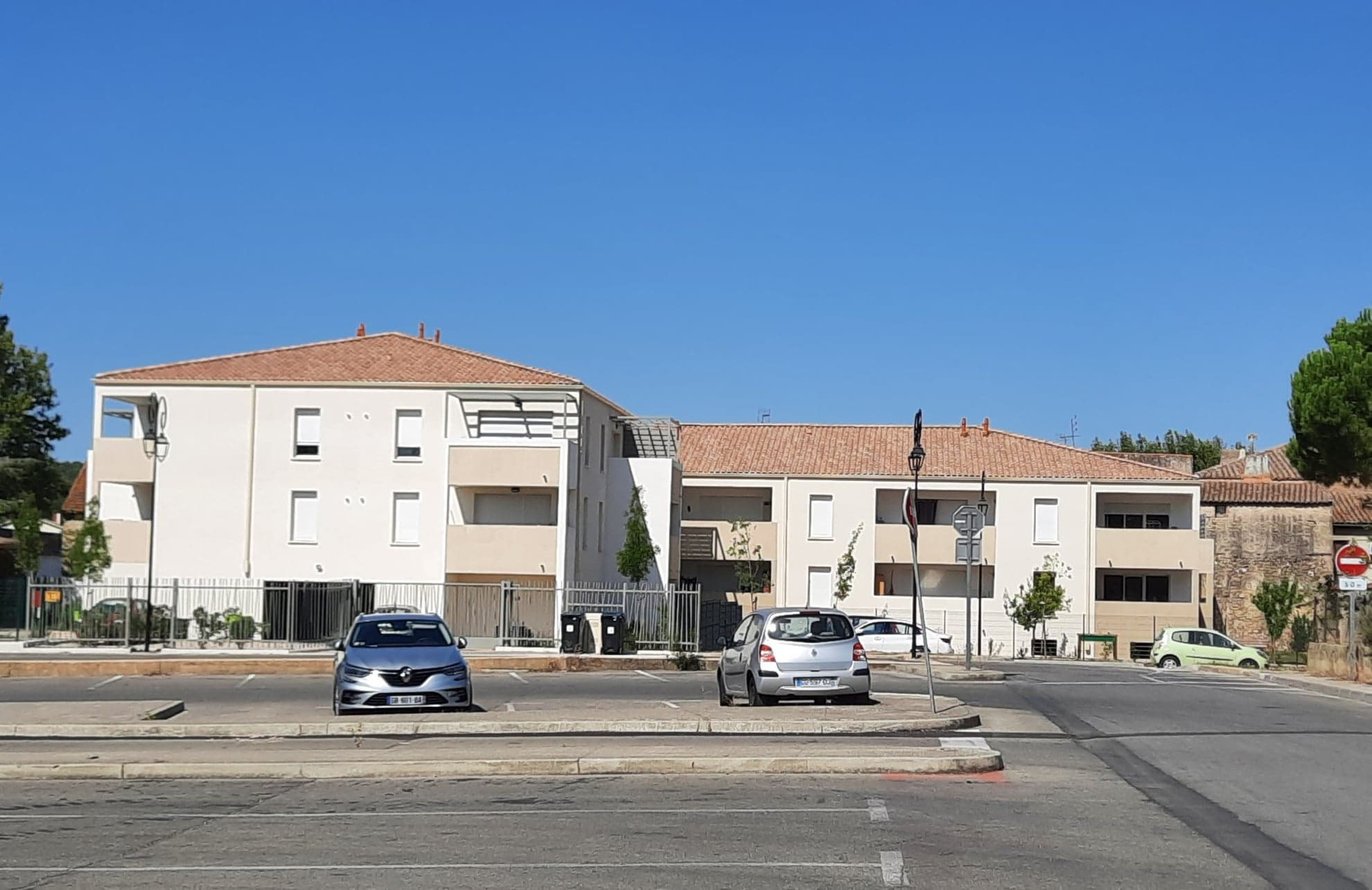Résidence de deux étages aux toits de tuiles, avec loggias et terrasses, vue depuis la rue