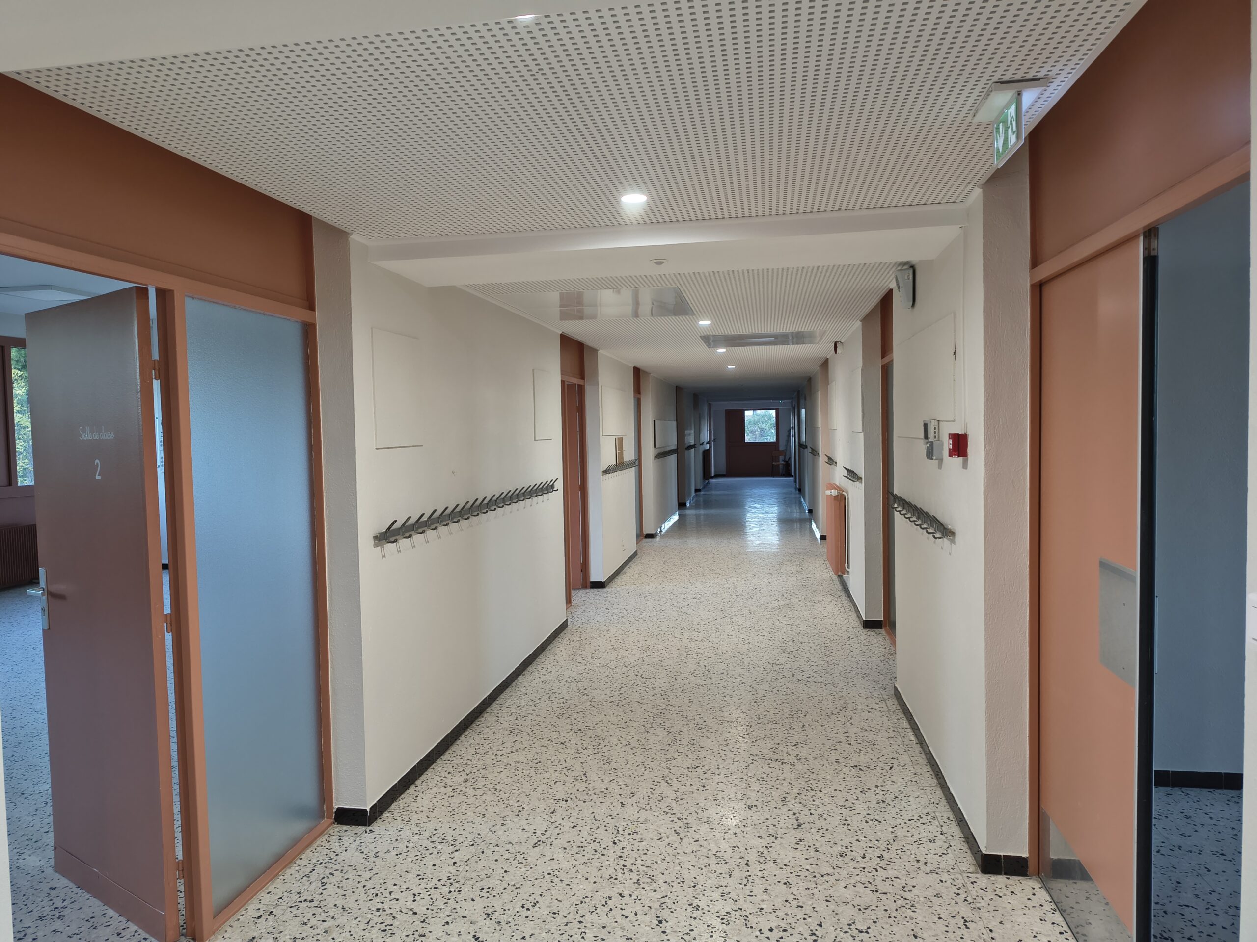 Couloir rénové du bâtiment Albert-Camus, sol en granito et portes de classes saumon
