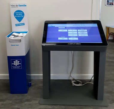 Borne à écran tactile et présentoir de dépliants de la Caisse d’allocations familiales dans la salle de France Services
