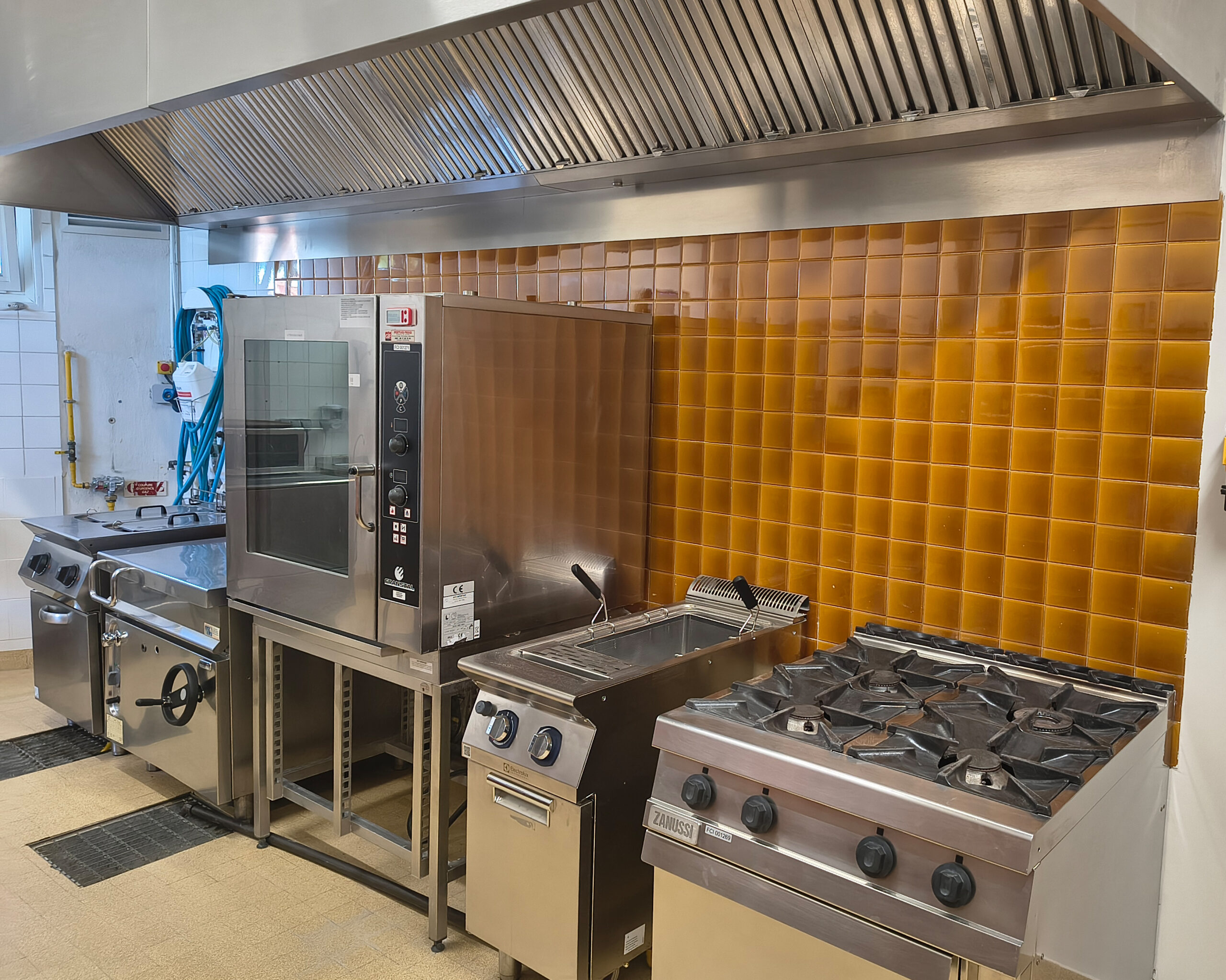 La cuisine de la cantine, avec son four mixte, ses friteuses et ses feux sous la hotte