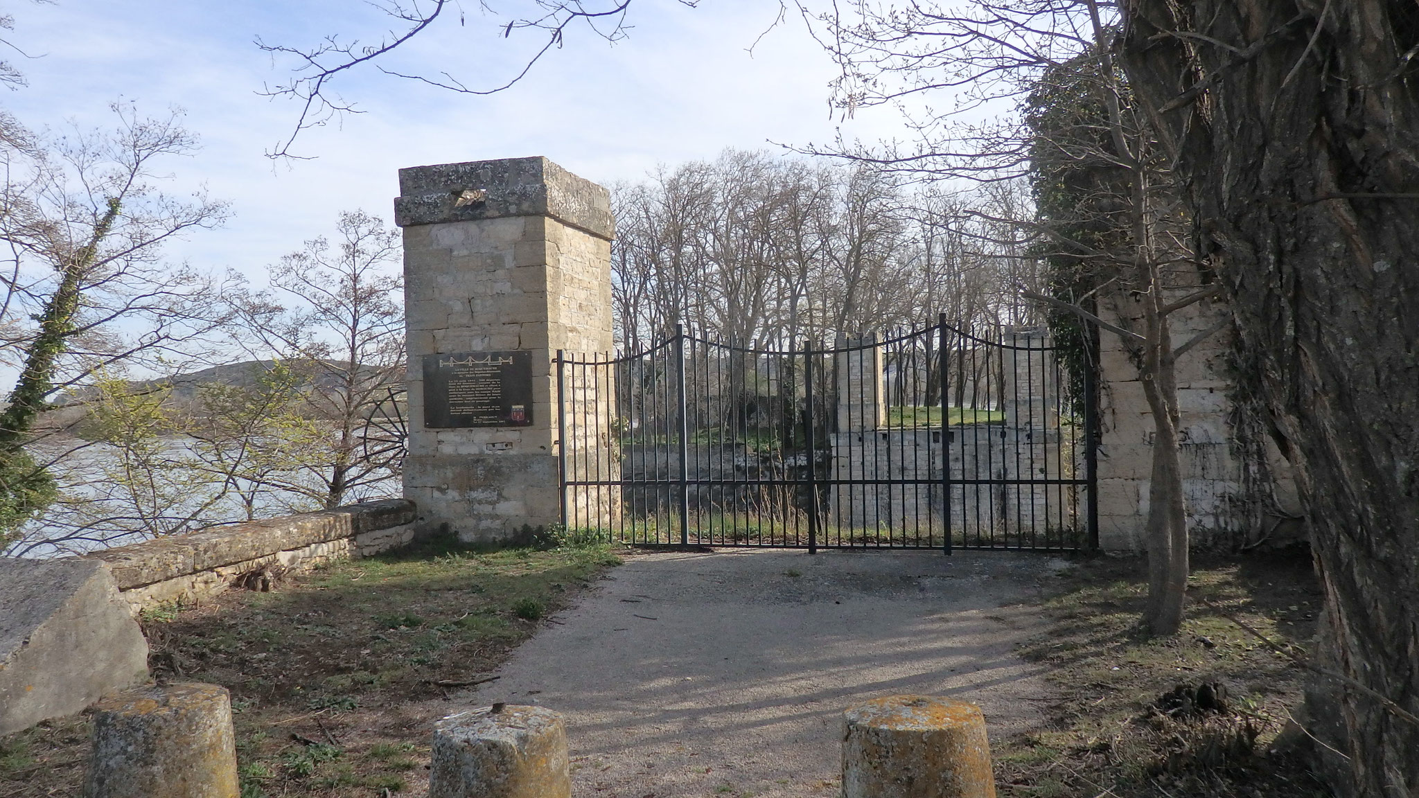 Pilier en pierre portant la plaque en mémoire des déportés-résistants du Train fantôme, à côté d’une grille, au bord du Rhône