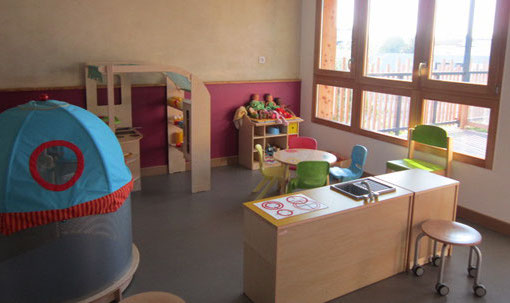 Salle du relais aménagée pour les tout-petits : tente de jeu, dînette, petites tables et chaises colorées