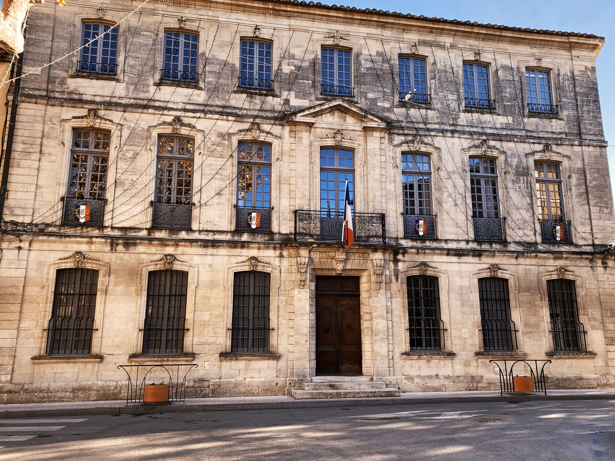 Façade en pierre de l’hôtel de ville sur trois niveaux, balcon central au drapeau tricolore