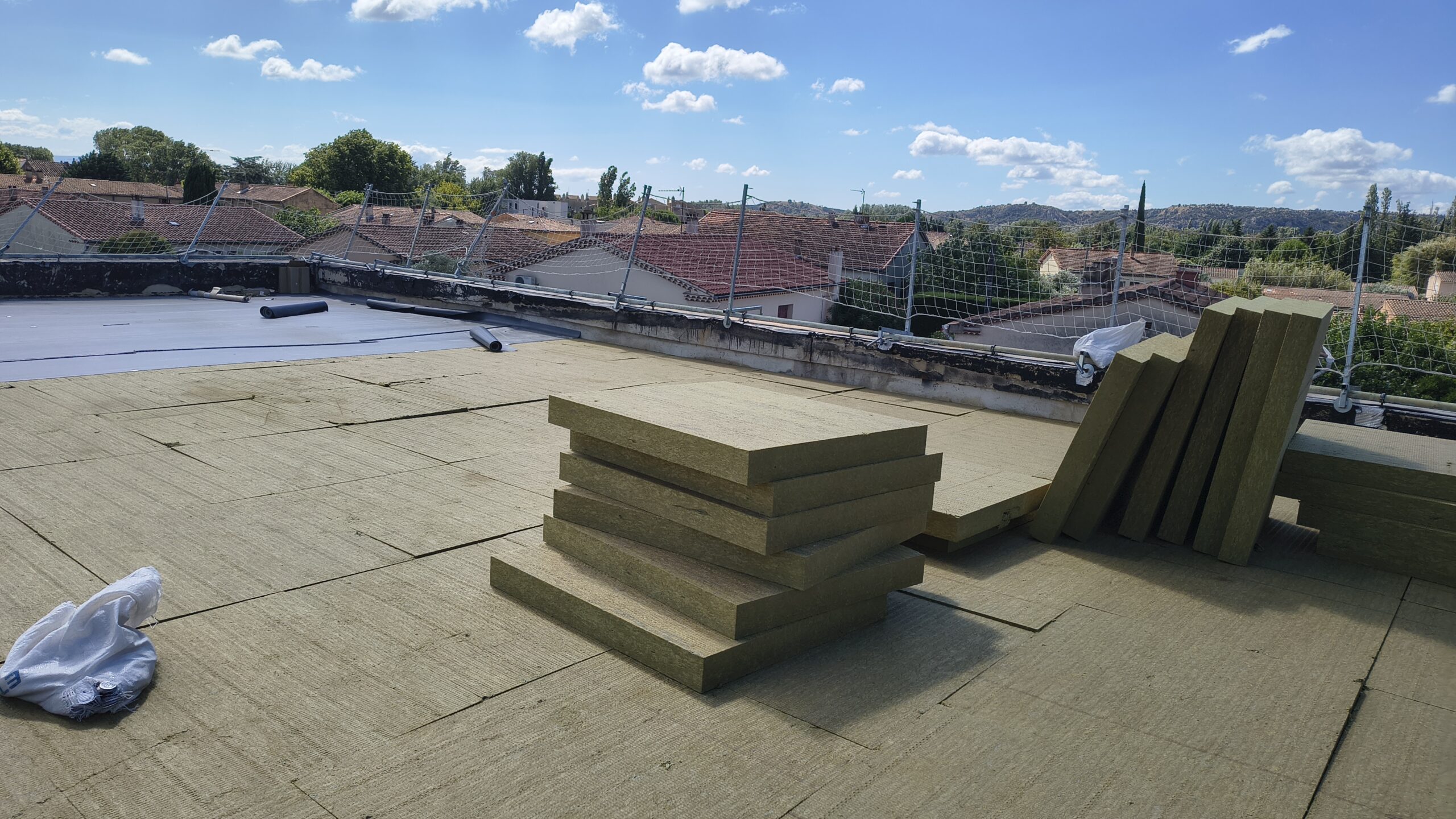 Panneaux d’isolant posés sur la toiture-terrasse, avec vue sur les toits du village