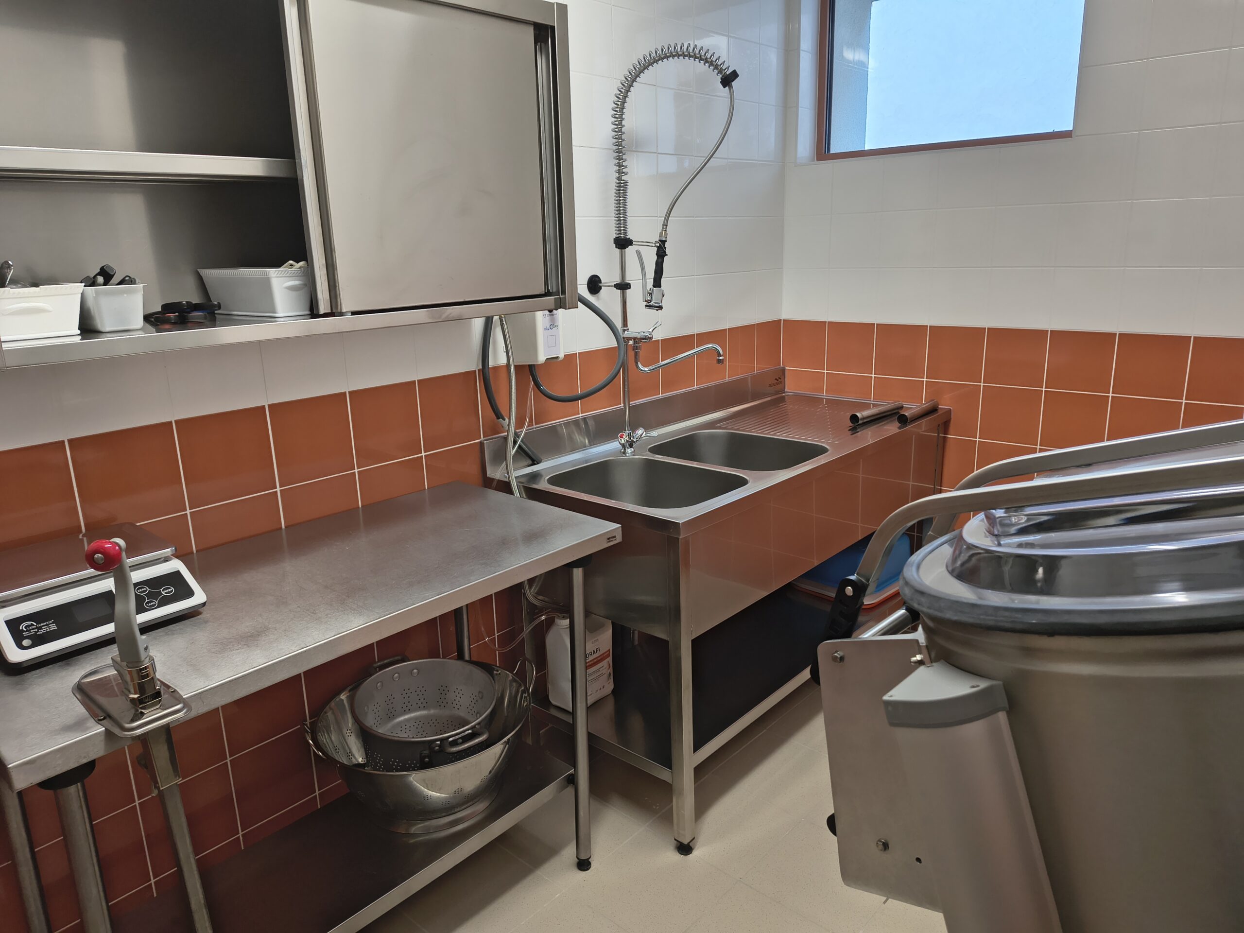 Poste de préparation en inox avec double bac et douchette dans la cuisine rénovée