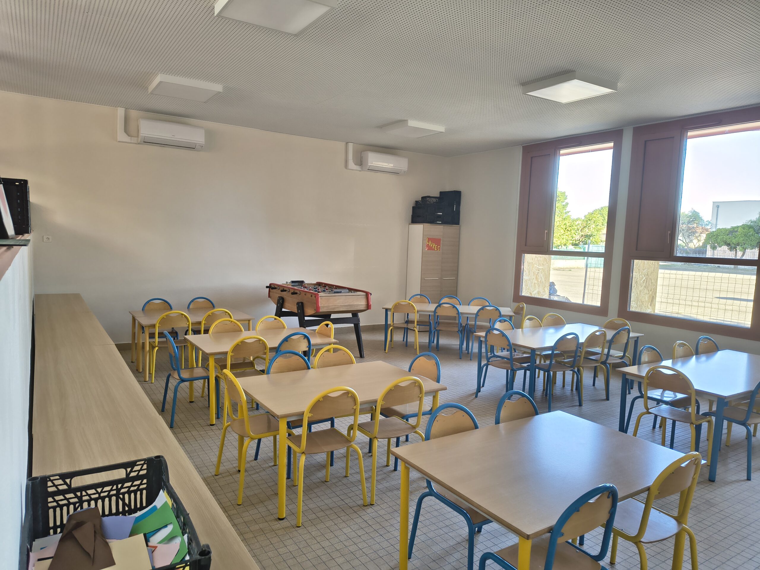 Salle de La Récré rénovée, avec tables et chaises d’enfants et un baby-foot